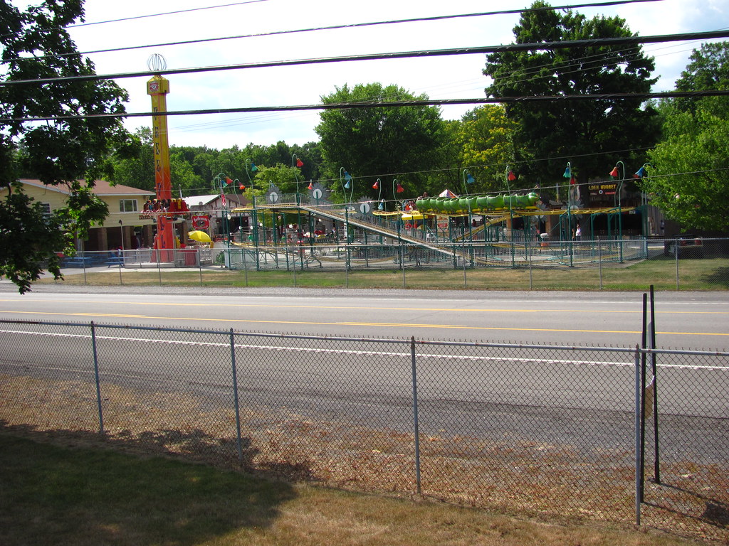 A walkway and rides at an amusement park on a bright day