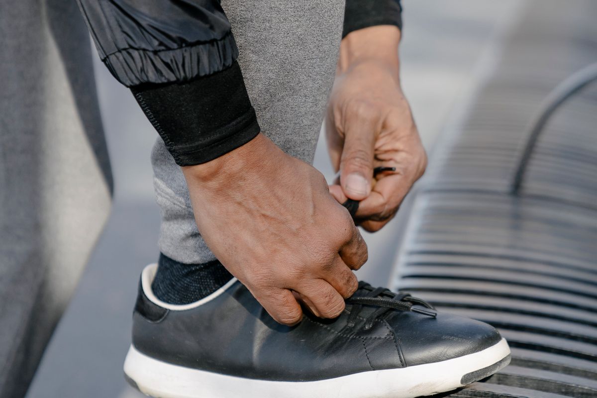 Close-up of hands tying sneaker laces on a city street