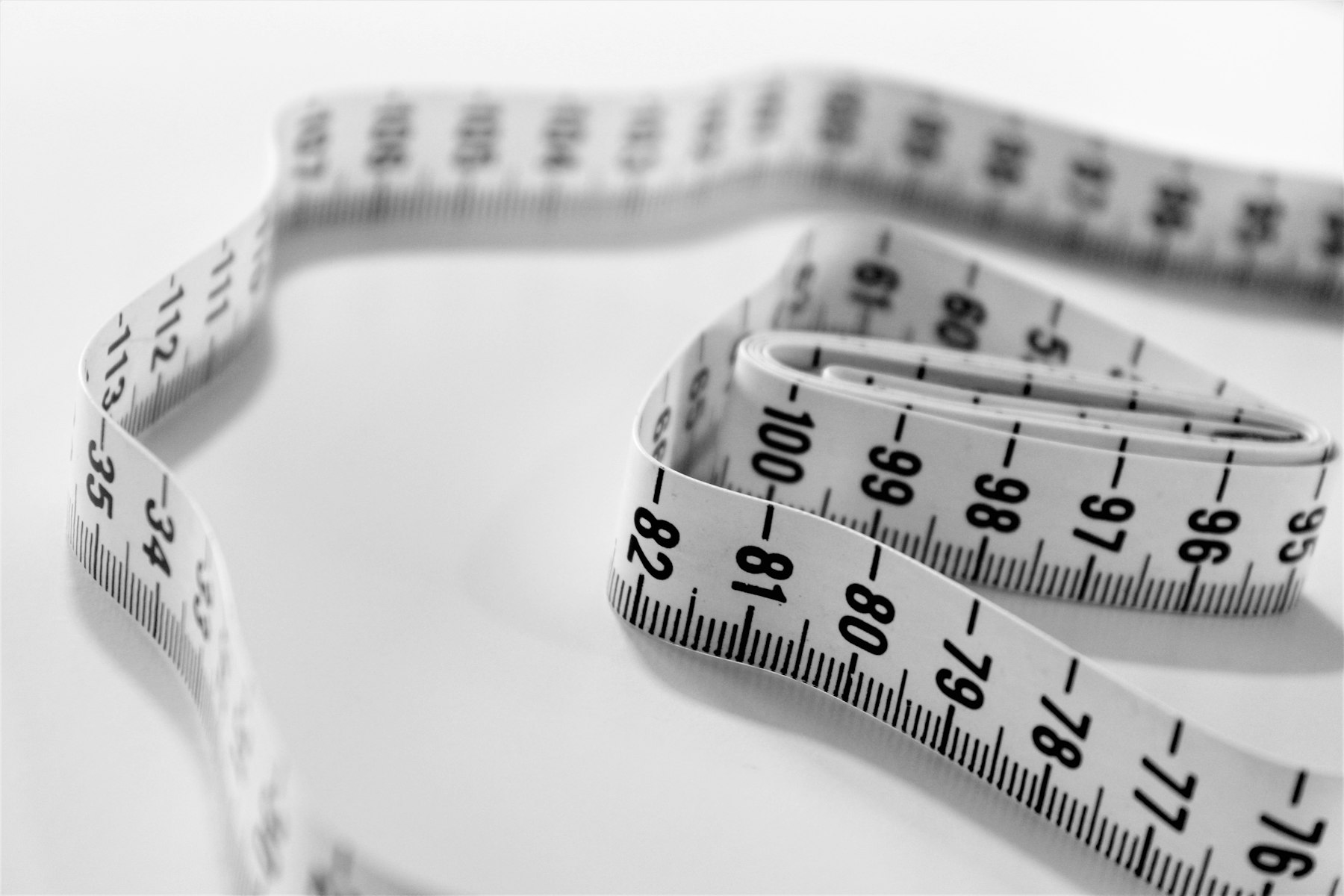 A coiled cloth measuring tape showing shoe-scale centimeter and inch markings