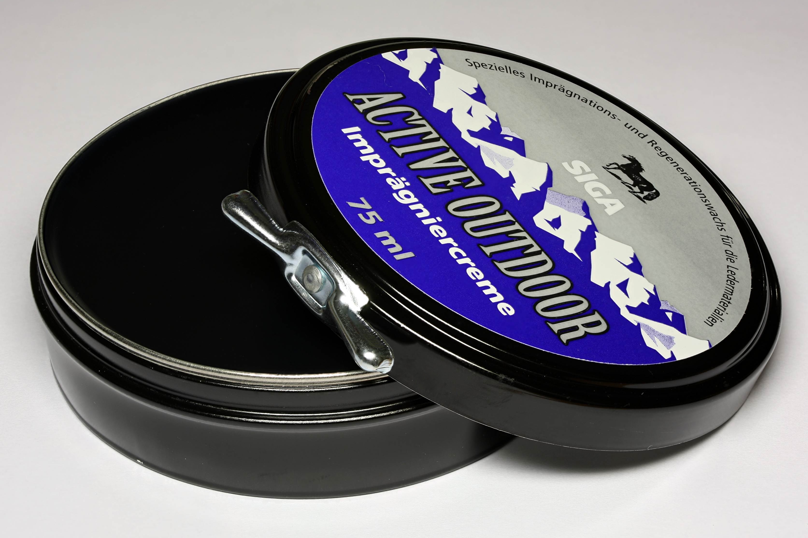 An open can of shoe polish beside a brush