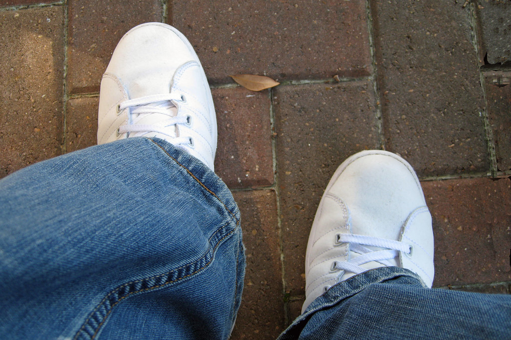 A pair of white sneakers standing on pavement